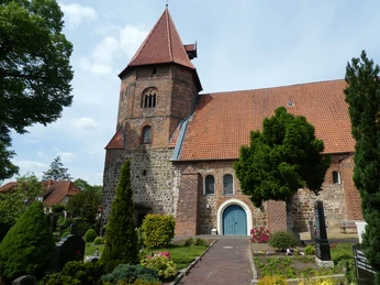 St. Laurentius-Kirche Achim St. Laurentius-Kirche in Achim mit Ziegeldach, Turm und umgebenden grünen Bäumen und Blumenbeeten.