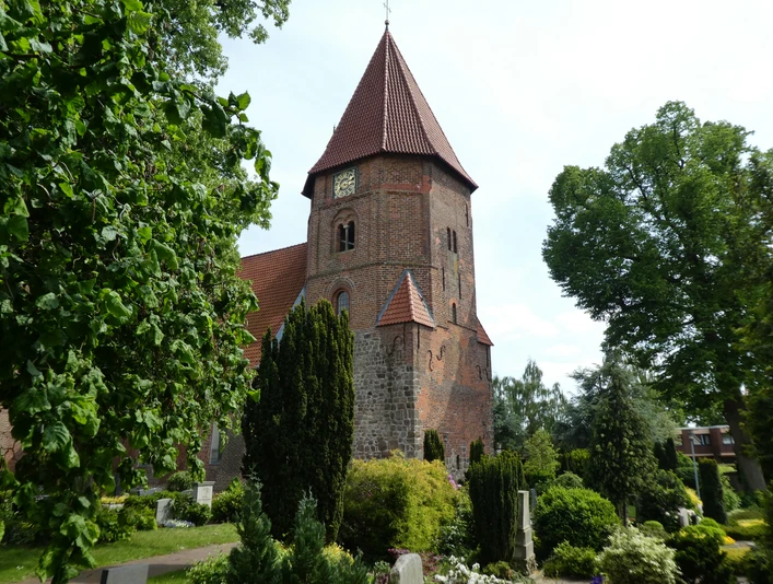 St. Laurentius-Kirche Achim Backsteinkirche mit markantem Turm und rotem Dach, umgeben von gepflegtem Grün und Baumbestand.