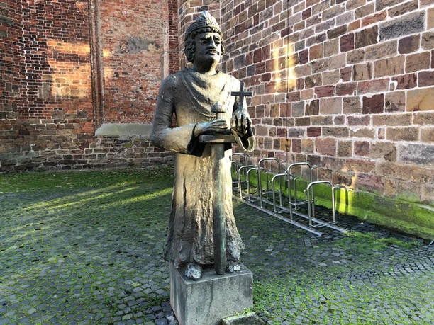 An outdoor historical statue of Charlemagne, surrounded by old brick walls and cobblestones.