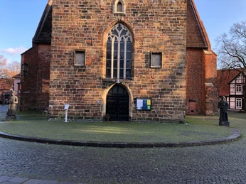 Karl der Große und Widukind Backsteingebäude mit spitzem Dach und einer Statue auf jeder Seite, bei sonnigem Wetter fotografiert.