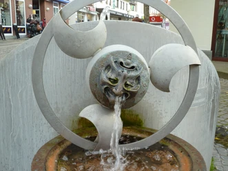 Wasserspielbrunnen "Faszination Wasser" mit skulpturalem Gesicht, aus dessen Mund Wasser fließt.