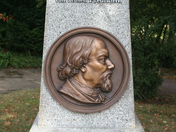 Oppermann Denkmal Bronzeplakette eines Mannes in Seitenansicht auf einem steinernen Sockel in einem Park.