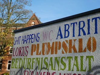 Öffentliches WC Parkplatz Rathaus Achim Bunte Schriftzüge auf einer Wand markieren ein öffentliches WC in der Nähe des Rathauses von Achim.