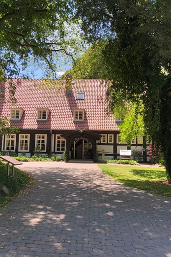 Forsthaus Heiligenberg Ein traditionelles Fachwerkhaus mit rotem Ziegeldach, eingebettet in üppigem, grünen Baumbestand.