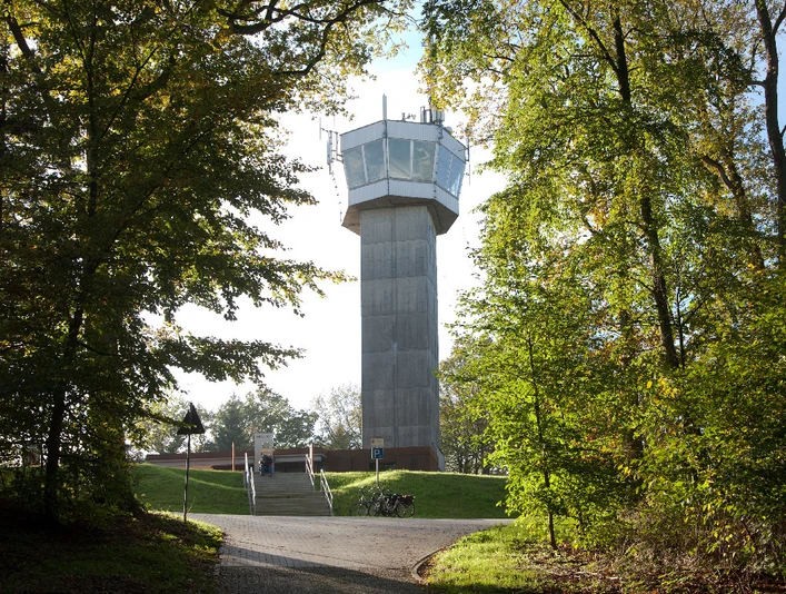 Wingst Aussichtsturm Deutscher Olymp Aussichtsturm Deutscher Olymp im Wald, von Sonnenlicht umgeben, mit Weg und Fahrrädern davor.German Olympus observation tower in the forest, surrounded by sunlight, with path and bicycles in front of it.Det tyske Olympus-observationstårn i skoven, omgivet af sollys, med sti og cykler foran.Duitse Olympus uitkijktoren in het bos, omgeven door zonlicht, met pad en fietsen ervoor.