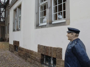 Lechner Figur Petershagen-Altes Amtsgericht Eine Skulptur eines Polizeiwächters steht vor einem alten Fachwerkgebäude in Petershagen.