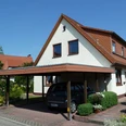 Einfamilienhaus mit Carport und gepflegtem Garten, unter blauem Himmel in ruhiger Umgebung.