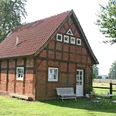 Ferienhof Wikner Fachwerkhaus auf einem grünen Hof mit Gartenmöbeln, umgeben von Bäumen und ländlicher Landschaft.