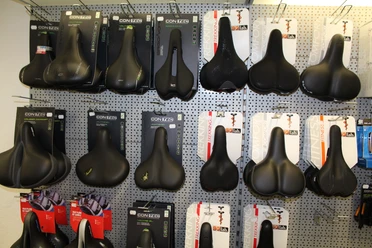 Verschiedene Fahrradsättel in einem Geschäft, ordentlich in Regalen angeordnet, an einer Wand ausgestellt.