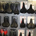 Verschiedene Fahrradsättel in einem Geschäft, ordentlich in Regalen angeordnet, an einer Wand ausgestellt.