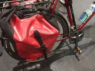 Rote Fahrradtasche aus wasserdichtem Material an einem Fahrradrahmen, geschützt vor Regen.