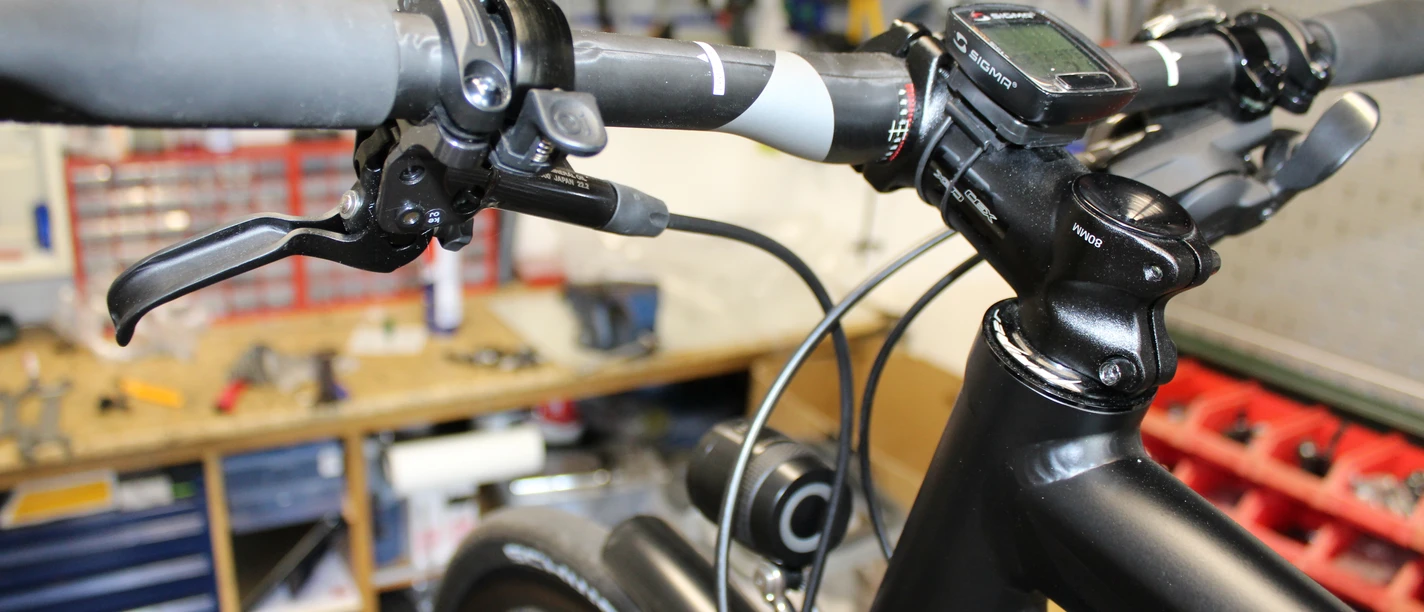 Fahrradlenker in einer Werkstatt, umgeben von Werkzeug, geeignet für Radpflege und Reparaturarbeiten.