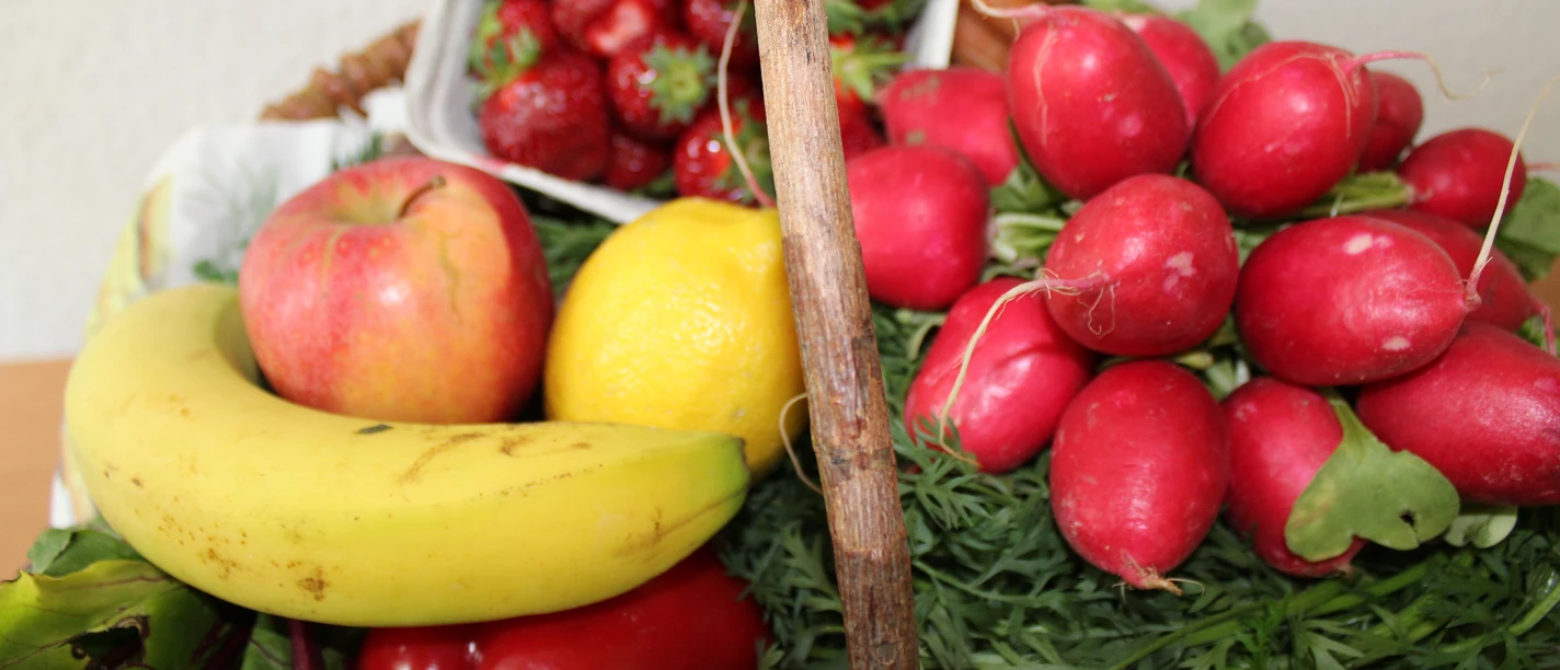 Obst und Gemüse Frisches Obst und Gemüse arrangiert in einem Korb, darunter Banane, Erdbeeren, Radieschen.