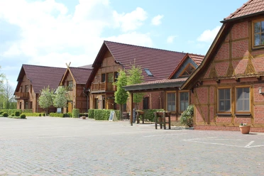 Okelmann's Historisches Hotelgebäude aus rotem Backstein mit Holzdetails, umgeben von einer gepflasterten Fläche.