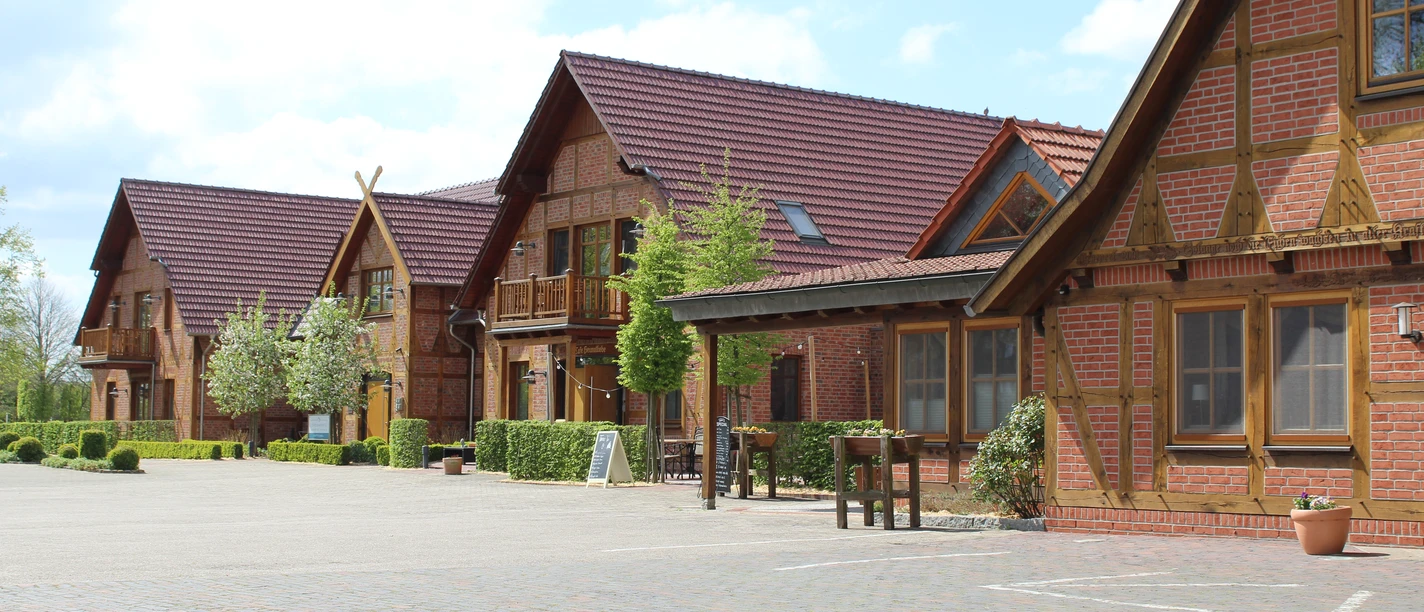 Okelmann's Historisches Hotelgebäude aus rotem Backstein mit Holzdetails, umgeben von einer gepflasterten Fläche.