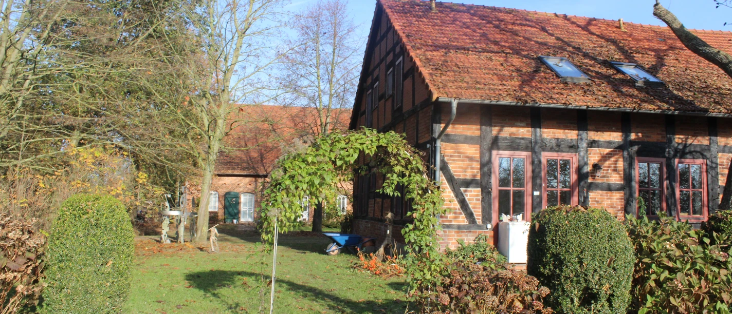 Adelheidshof Ein traditionelles Fachwerkhaus mit roten Ziegeln und gepflegtem Garten unter blauem Himmel.