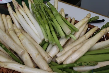 Nienburger Spargel Weiße und grüne Spargelstangen in einem Korb, frisch geerntet und gestapelt.