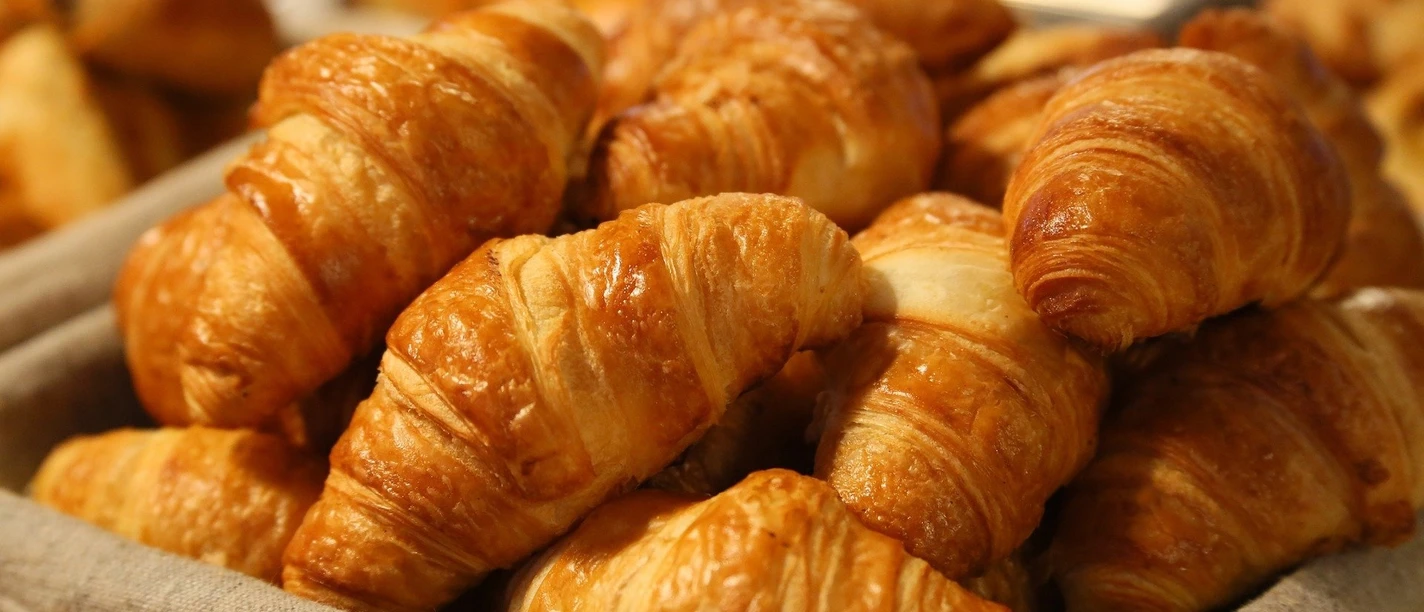 bread-1284438_1920.jpg Ein Korb mit knusprigen Croissants aus goldenem Blätterteig, frisch gebacken und appetitlich angerichtet.
