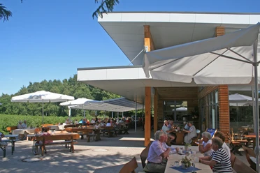 Mensen genieten van zonnige uren op het buitenterras van een café met moderne, witte parasols.