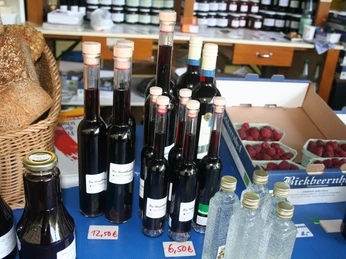 Bickbeernhof Blaubeerprodukte Verschiedene Flaschen mit Blaubeerlikör stehen auf einem Tisch neben Brotkorb und frischen Beeren.