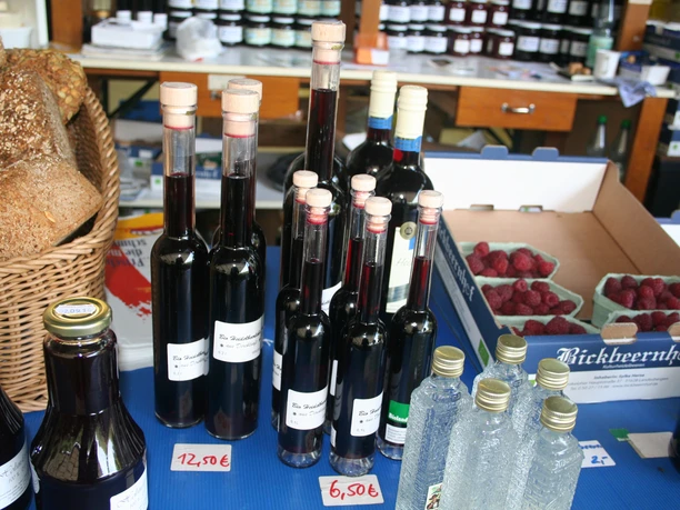 Bickbeernhof Blaubeerprodukte Verschiedene Flaschen mit Blaubeerlikör stehen auf einem Tisch neben Brotkorb und frischen Beeren.