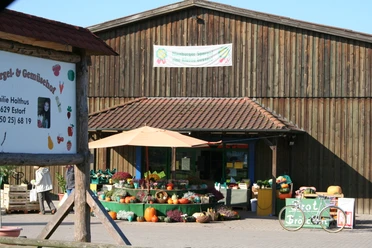Hofladen Holthus Hofladen Holthus bietet frisches Gemüse und Blumen vor einem rustikalen Holzgebäude mit Schildern.