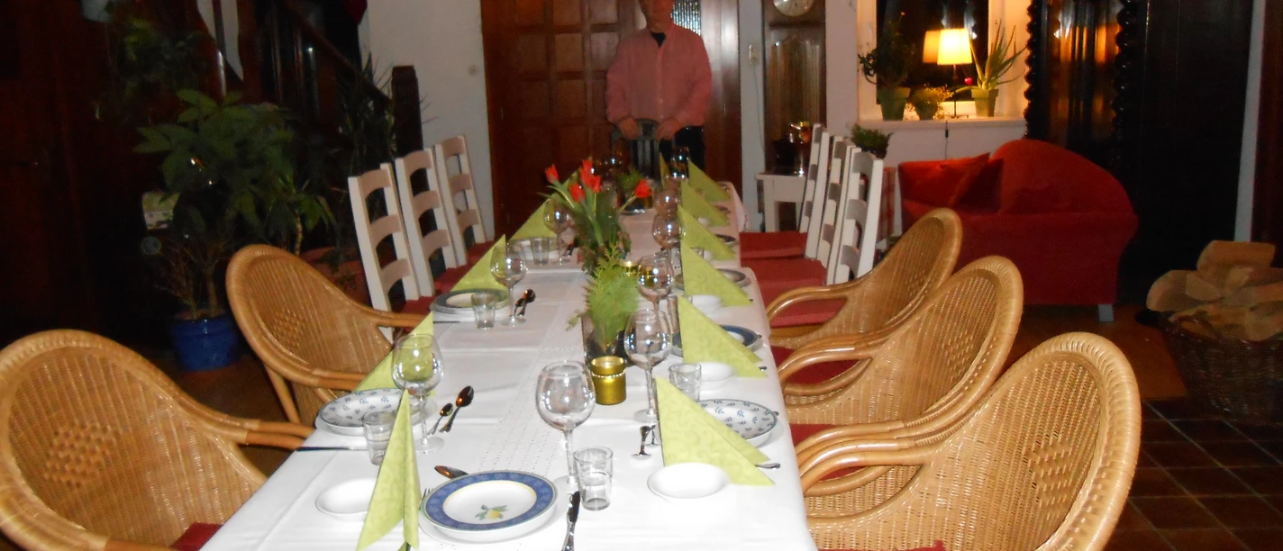 A festively laid table in a brightly lit room with rustic furniture and plants.