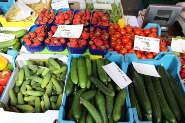 Gemüse Eine bunte Auswahl frischer Gurken, Tomaten und Erdbeeren, ordentlich auf einem Markt präsentiert.