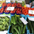 Gemüse Eine bunte Auswahl frischer Gurken, Tomaten und Erdbeeren, ordentlich auf einem Markt präsentiert.
