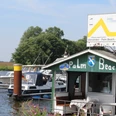 Am Ufer des Wassersportvereins Palm Beach Dörverden liegen Boote vor der mit Flaggen dekorierten Hütte.