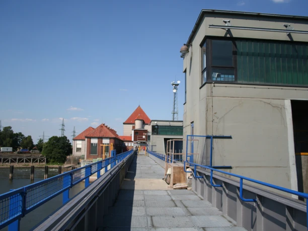 Dörverden barrage: Concrete and metal structures with striking red roofs under a clear sky.