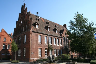 Historisches Backsteingebäude mit spitzem Giebel, hohen Fenstern und verzierten Dachgauben in Hoya.