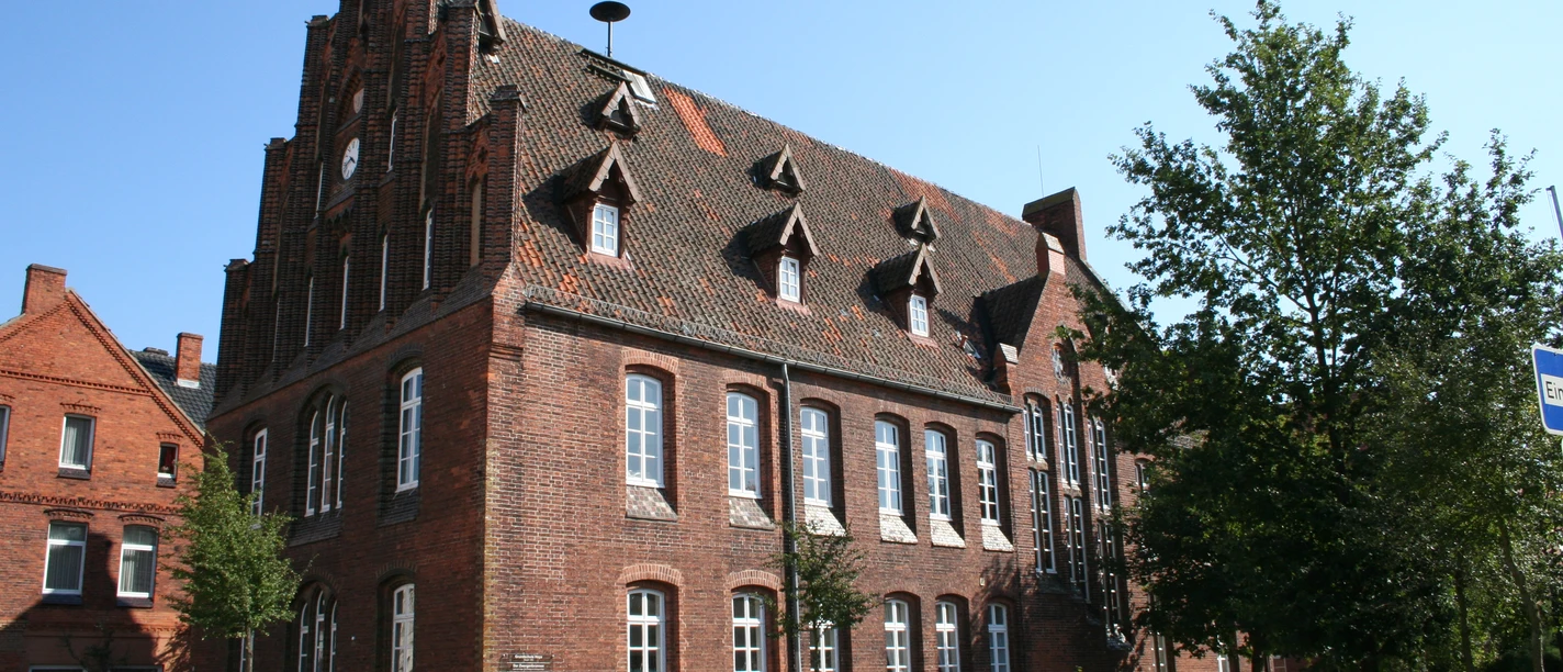 Grundschule Hoya Historisches Backsteingebäude mit spitzem Giebel, hohen Fenstern und verzierten Dachgauben in Hoya.
