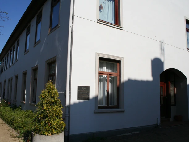 Mohrhoff-Haus: Ein zweigeschossiges, weißes Gebäude mit dunklen Fenstern unter klarem Himmel.