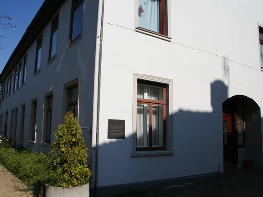 Mohrhoff-Haus Mohrhoff-Haus: Ein zweigeschossiges, weißes Gebäude mit dunklen Fenstern unter klarem Himmel.