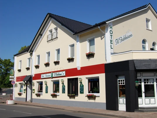 Hotel Il Gabbiano Gelb gestrichenes Hotel mit rotem Detail, großen Fenstern, und Eingang unter blauem Himmel.