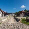 Weitblick auf Schloss Benkhausen Blick über eine gepflasterte Brücke auf Schloss Benkhausen und umgebende Fachwerkgebäude.