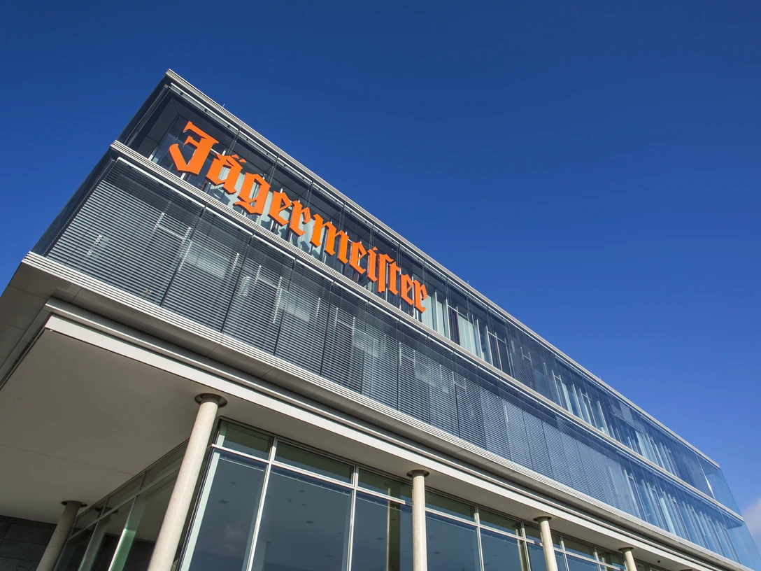 Modernes Glasgebäude der Firma Jägermeister unter blauem HimmelJägermeister's modern glass building under a blue skyJägermeisters moderne glasbygning under en blå himmelJägermeister's moderne glazen gebouw onder een blauwe hemel