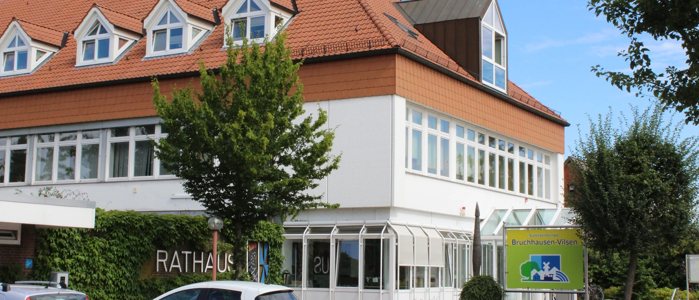 Rathaus Bruchhausen-Vilsen Rathaus Bruchhausen-Vilsen: Modernes Bauwerk mit spitzem Giebeldach, umgeben von grünen Bäumen.