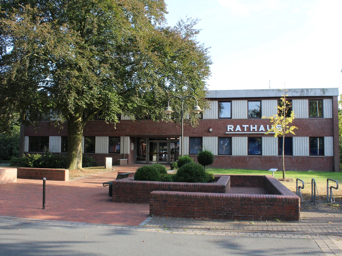 Rathaus Dörverden Der rote Backsteinbau des Rathauses Dörverden steht hinter grünen Bäumen und gepflegten Beeten.