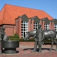 Rathaus Langwedel Rotes Backsteingebäude mit rotem Dach, davor Brunnen mit Figuren eines Pferdes und Menschen.