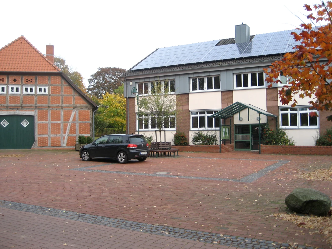 Rathaus Steimbke mit rotem Klinker und modernen Solarmodulen, umgeben von herbstlichem Laub.