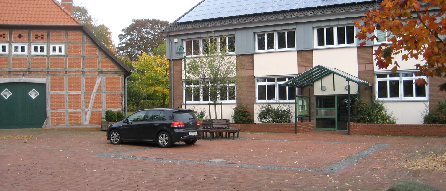Rathaus Steimbke mit rotem Klinker und modernen Solarmodulen, umgeben von herbstlichem Laub.