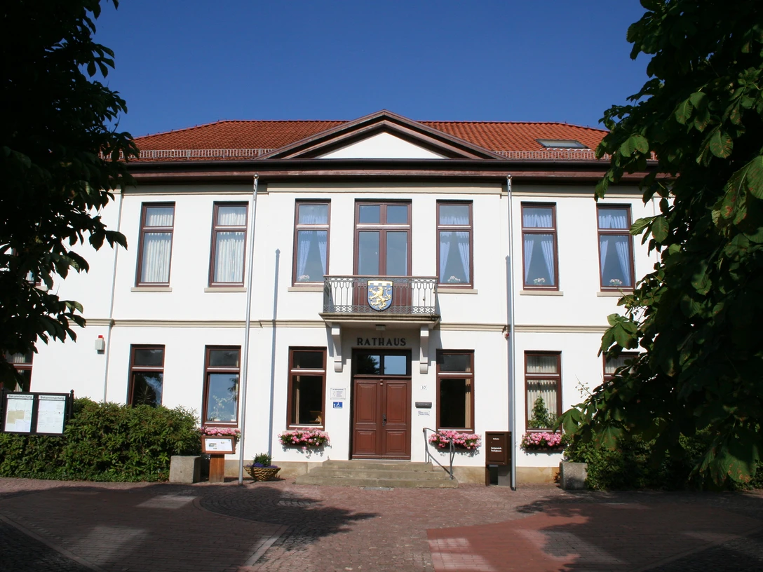 Rathaus Thedinghausen Das zweigeschossige, weiße Rathaus mit rotem Ziegeldach und zentralem Eingang ist von Bäumen umgeben.