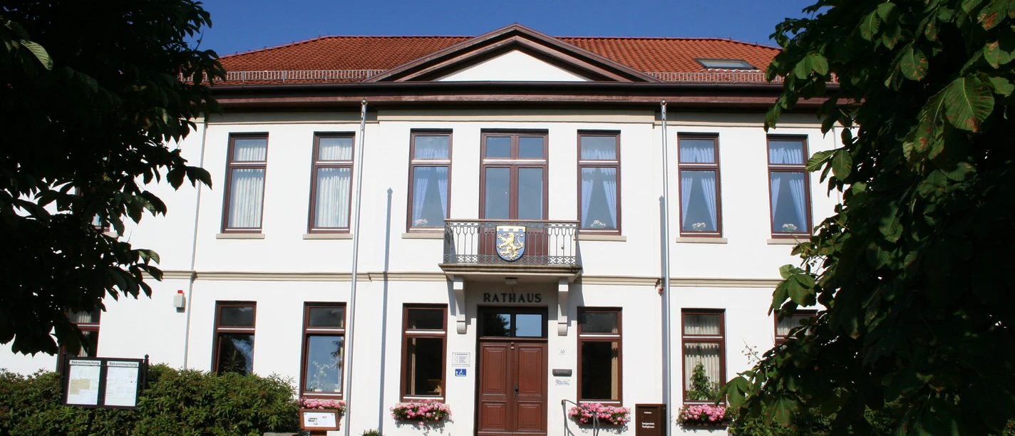 Rathaus Thedinghausen Das zweigeschossige, weiße Rathaus mit rotem Ziegeldach und zentralem Eingang ist von Bäumen umgeben.
