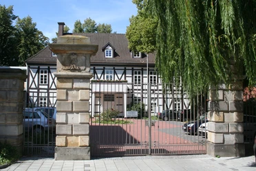 Altes Amtshaus Ein historisches Fachwerkhaus mit gepflegtem Garten, flankiert von mächtigen Steinsäulen.