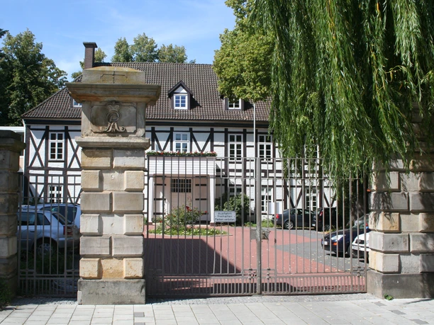 Altes Amtshaus Ein historisches Fachwerkhaus mit gepflegtem Garten, flankiert von mächtigen Steinsäulen.