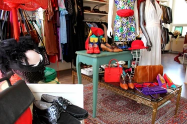 Polyestershock Ein detailreiches Vintage-Geschäft präsentiert farbenfrohe Kleidung und stilvolle Accessoires auf Tischen.
