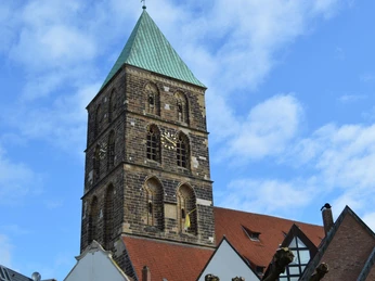 Kirchturm am Marktplatz in Rheine Der Kirchturm von Rheine ragt vor blauem Himmel empor, umgeben von Gebäuden mit spitzem Dach.