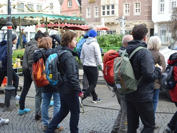 Wanderer auf dem Marktplatz von Rheine Eine Gruppe Wanderer mit Rucksäcken schlendert über den belebten Marktplatz von Rheine.